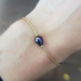 Gold bracelet and gray cultured pearl